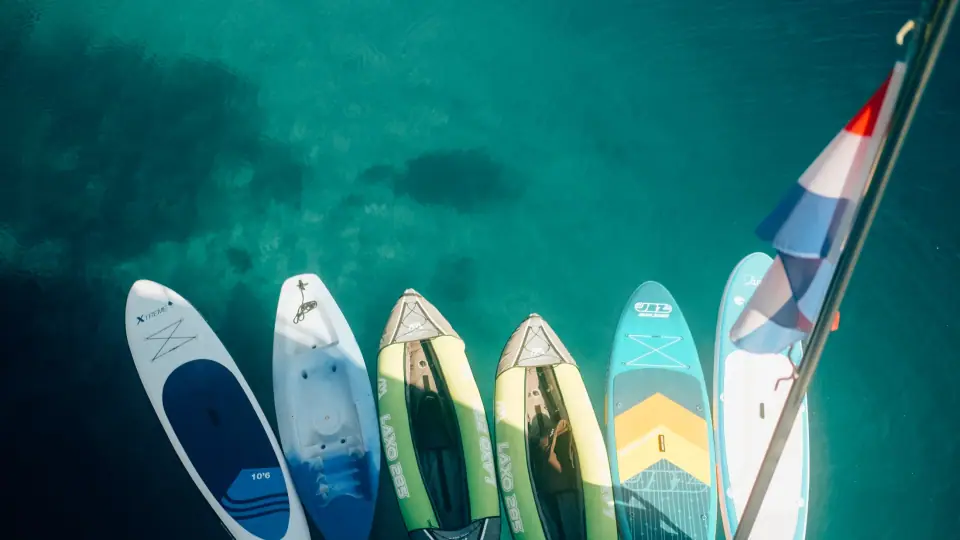Repeated paddleboard shapes border transparent teal water.