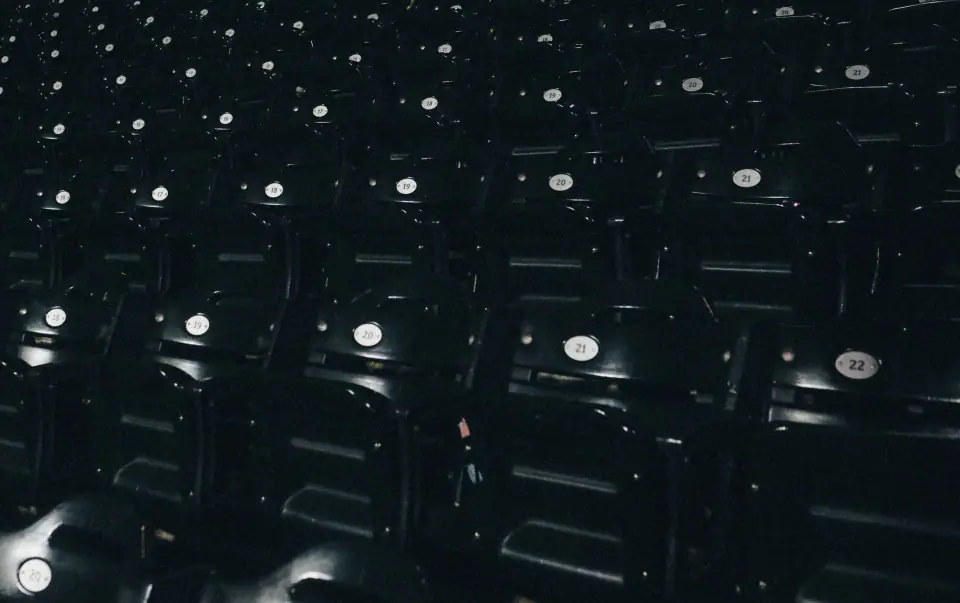 Rows of empty seats form a dark pattern dotted with highlights.