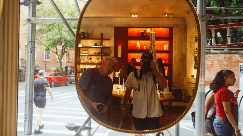 An oval mirror connects warm interior colors with the cooler street outside.