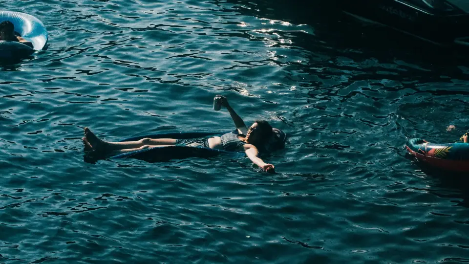 A reclining figure floats in textured blue water.
