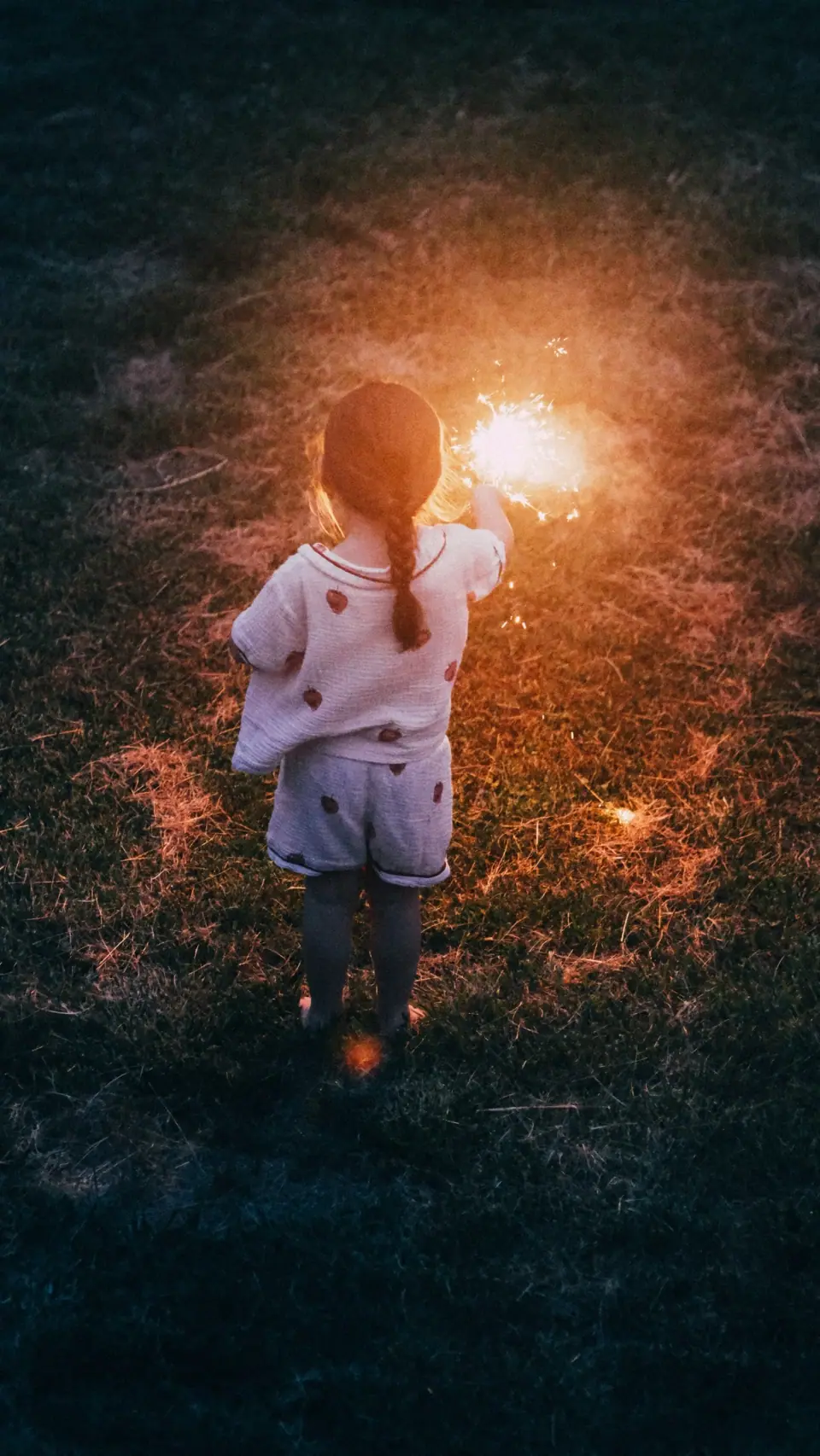 A small figure silhouetted beside a warm evening flare.