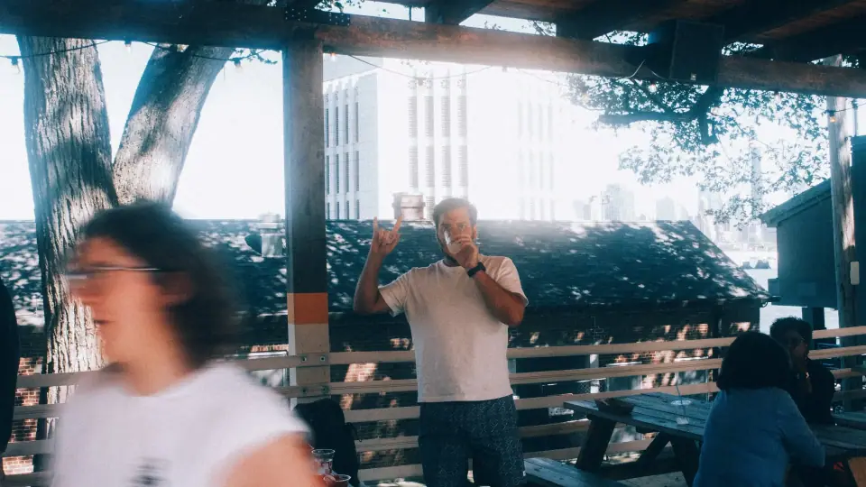 A blurred passerby crosses in front of a shaded gathering.
