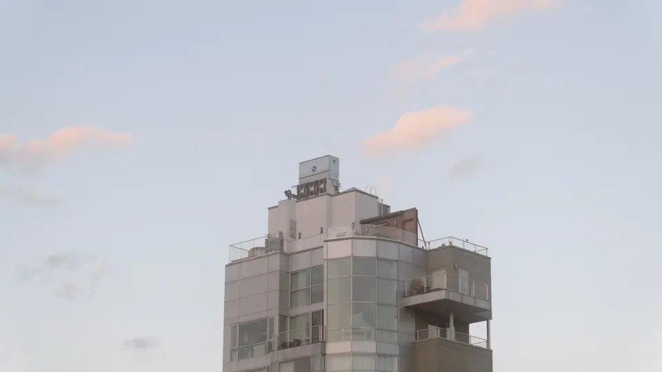 Small pink clouds sit above a pale building.