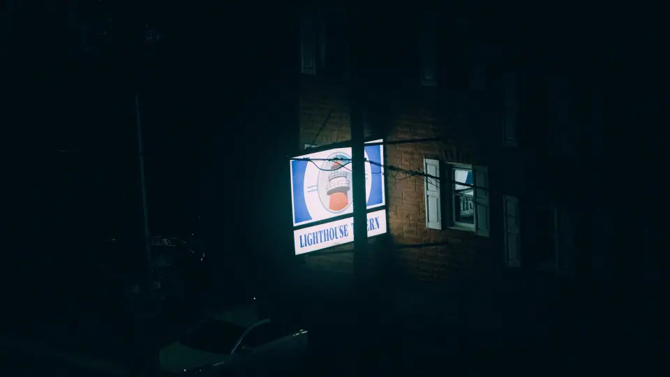 An isolated illuminated sign on a dark street.
