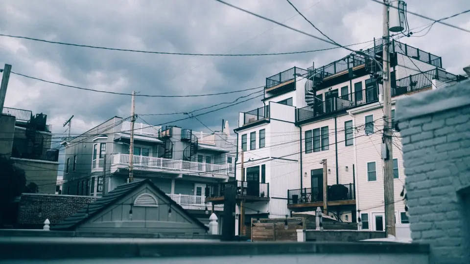 Overlapping roofs and wires form a dense pattern in cool tones.