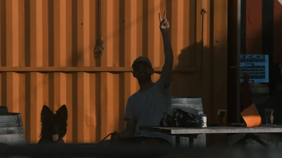 A raised arm, a dog, and an orange container share the frame.
