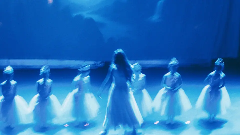 Blue motion blur softens dancers into a group of shapes.