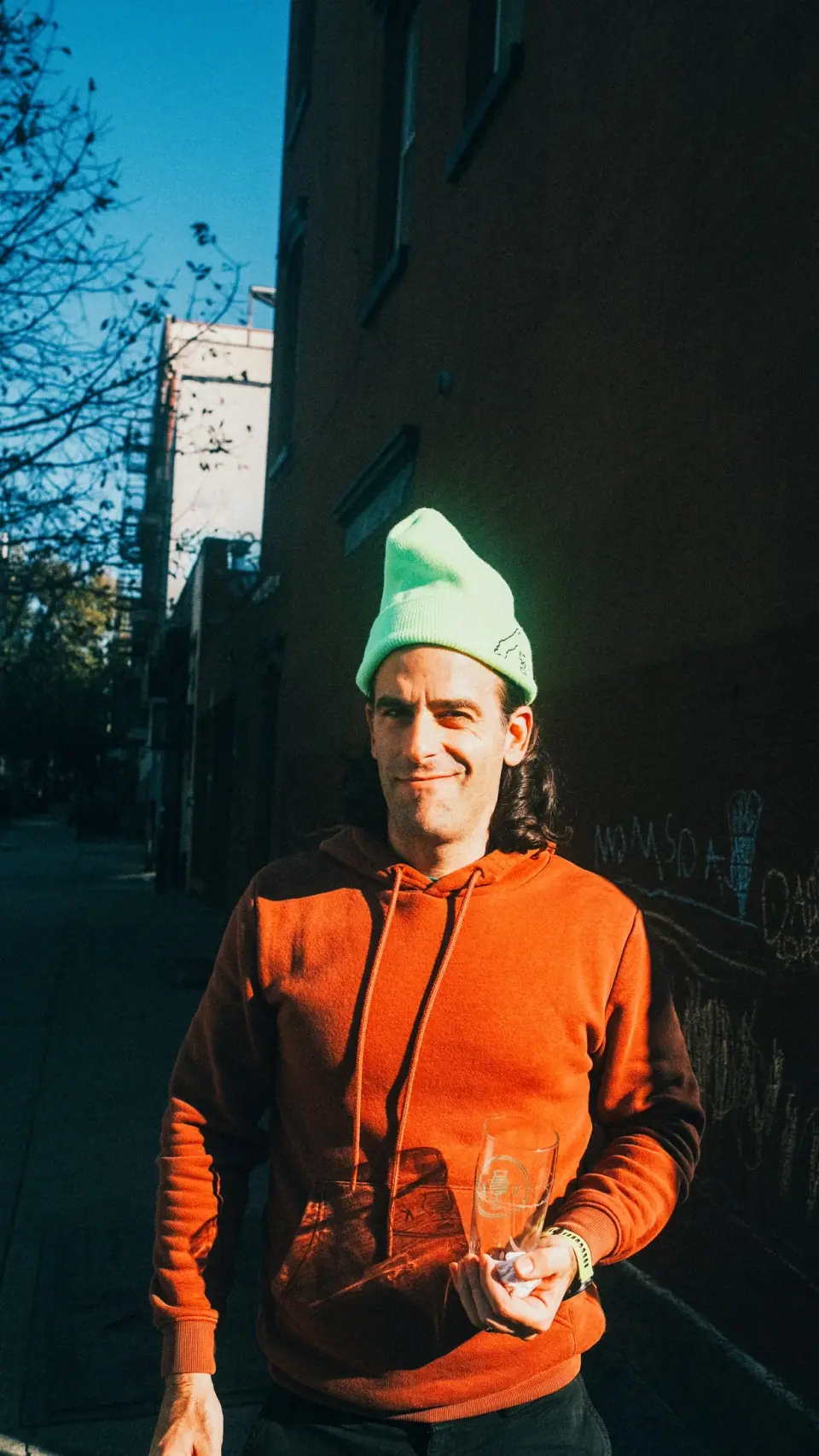 Orange clothing and a pale green hat against deep urban shadow.