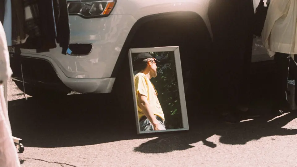 A mirror on the pavement reflects a portrait within the street.