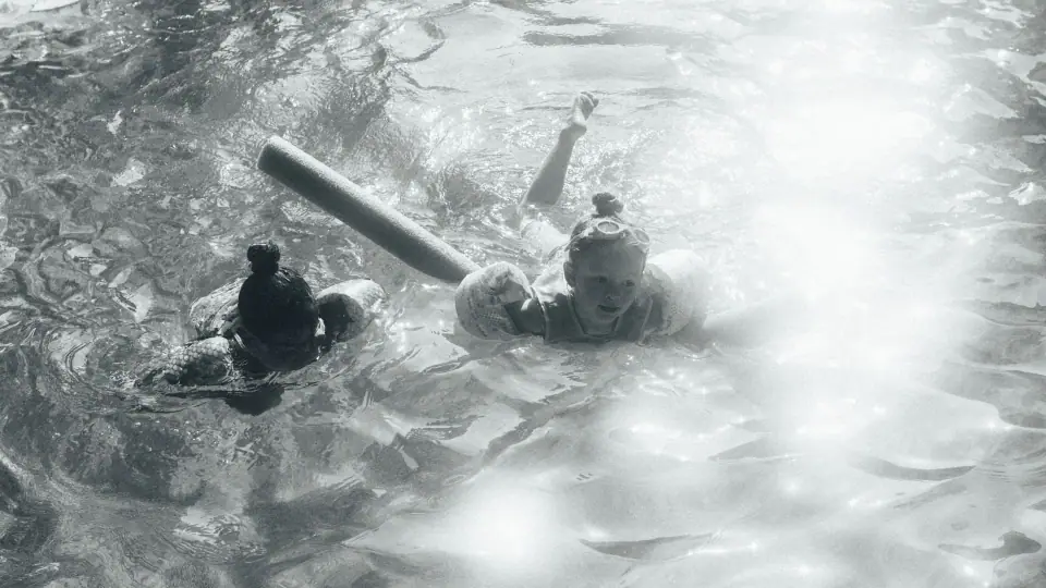 Figures softened by glare and water texture in monochrome.