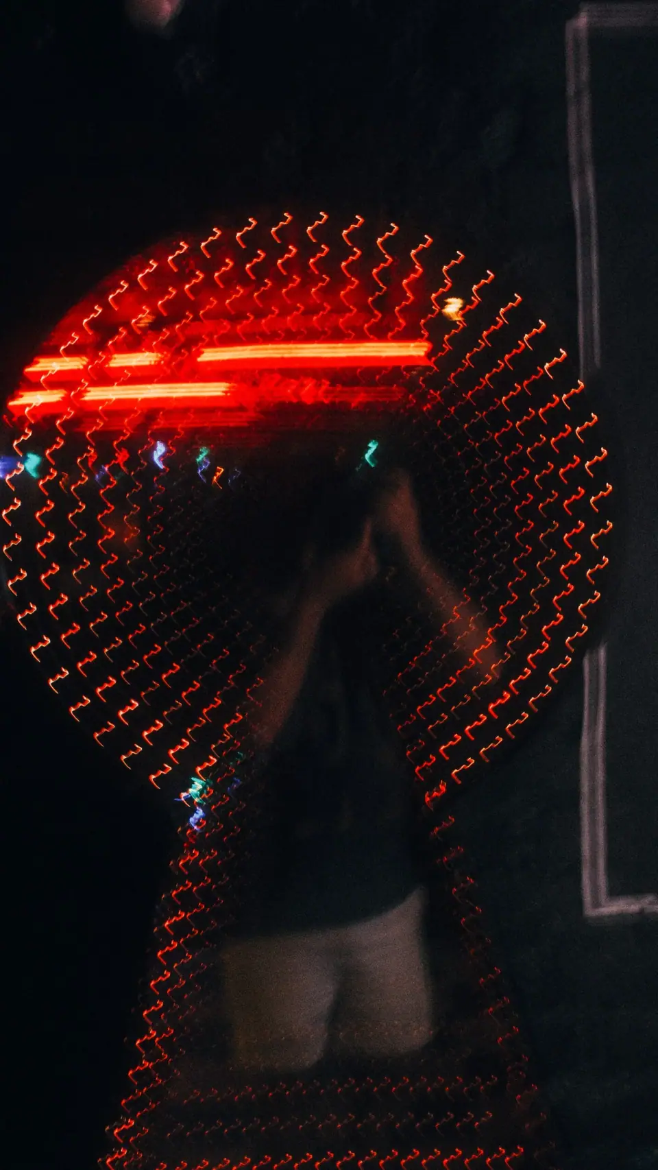 Red circular lights surround a fragmented reflected figure.