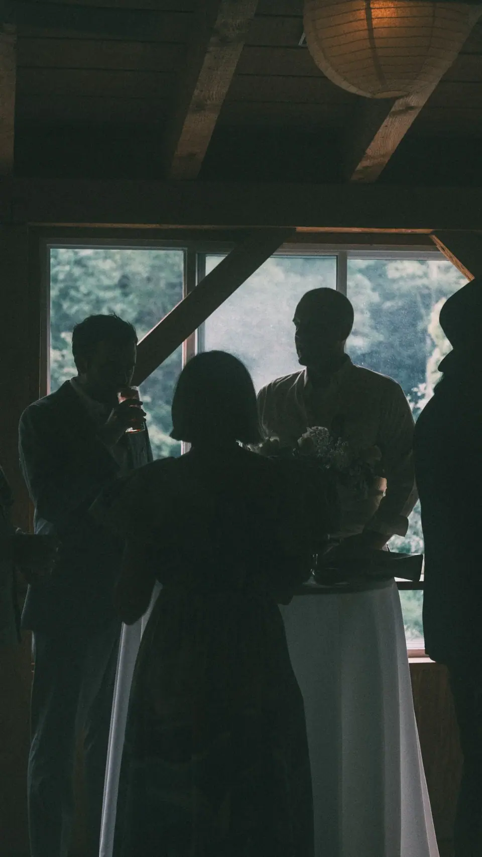 Dark interior silhouettes frame pale dresses and window light.