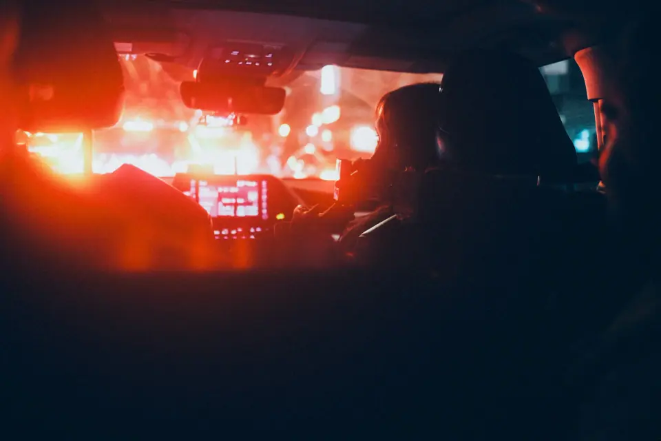 Red light fills a car interior around silhouetted figures.