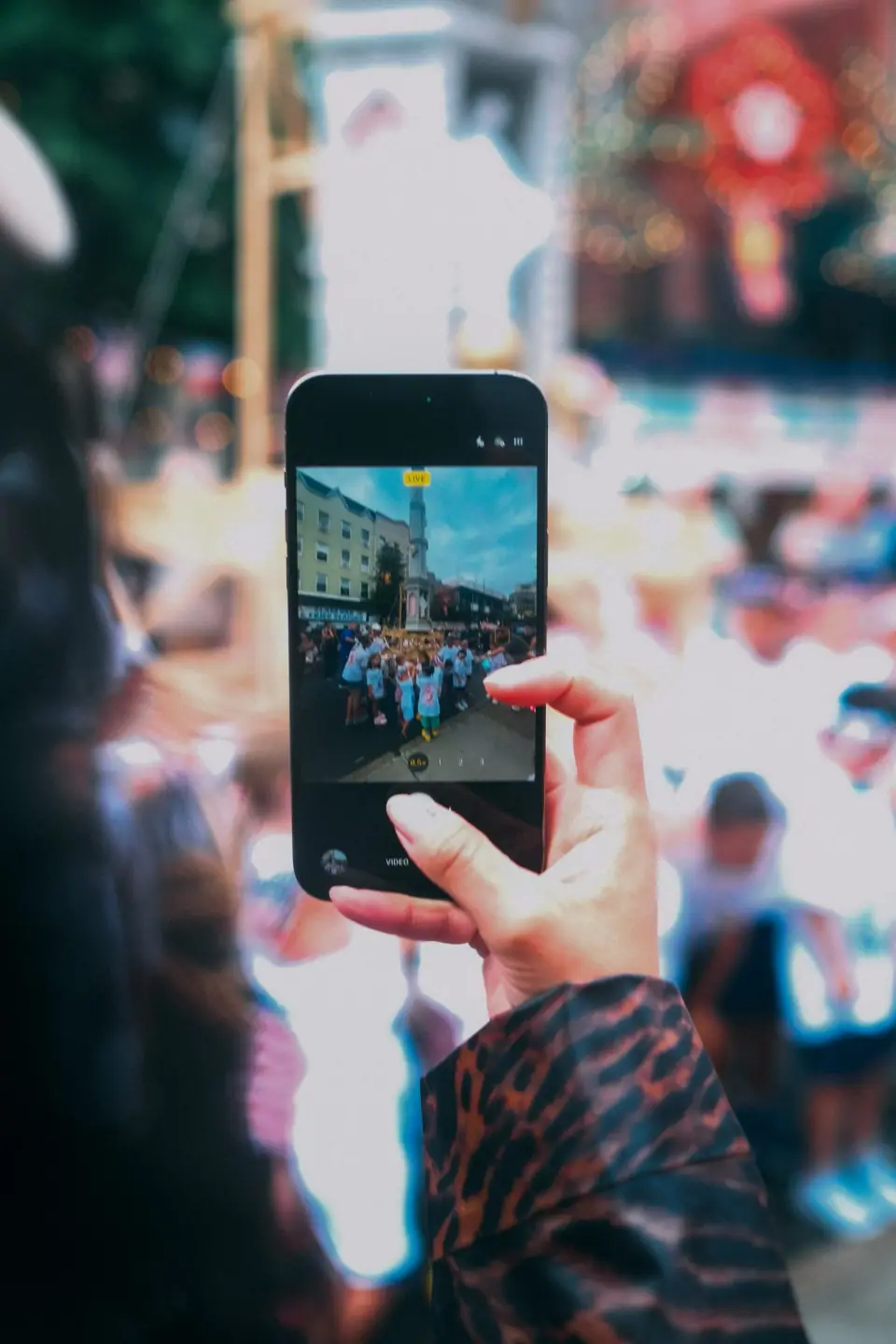 A phone screen shows a smaller image within a crowd.