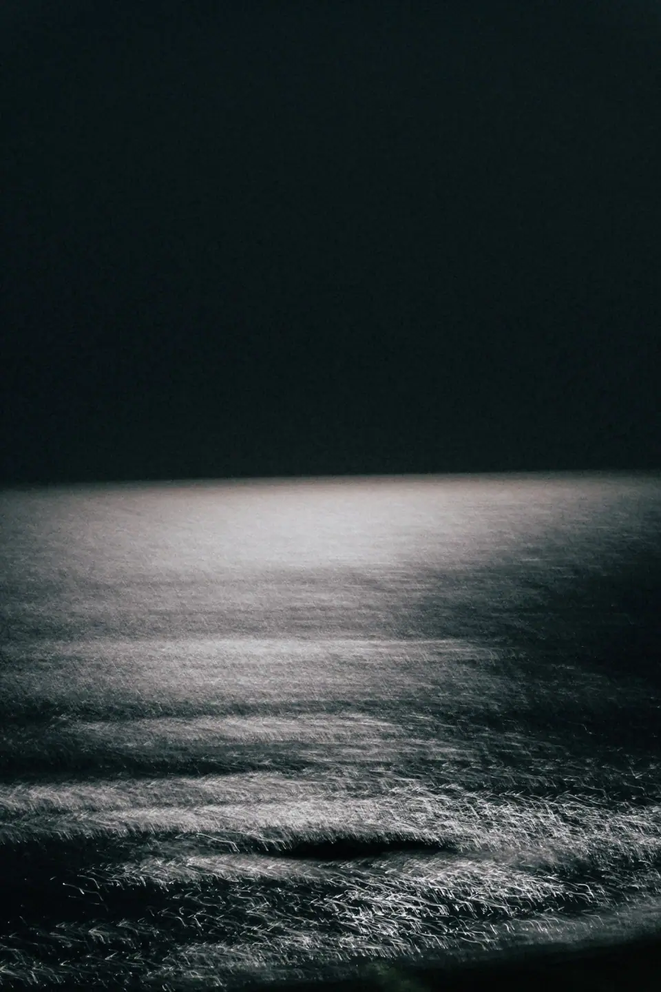 A narrow silver reflection in nearly black water.