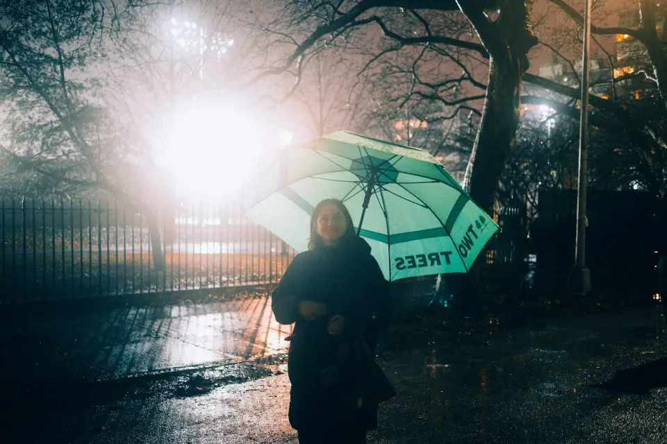 A night portrait with a green umbrella and bright flare.
