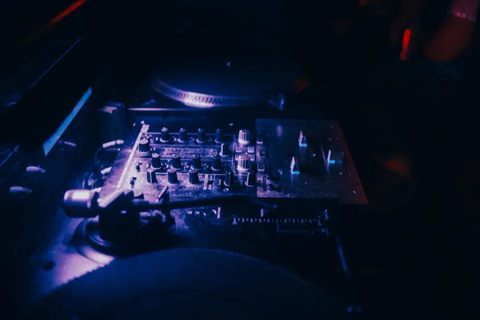 Turntables illuminated by violet light at night.