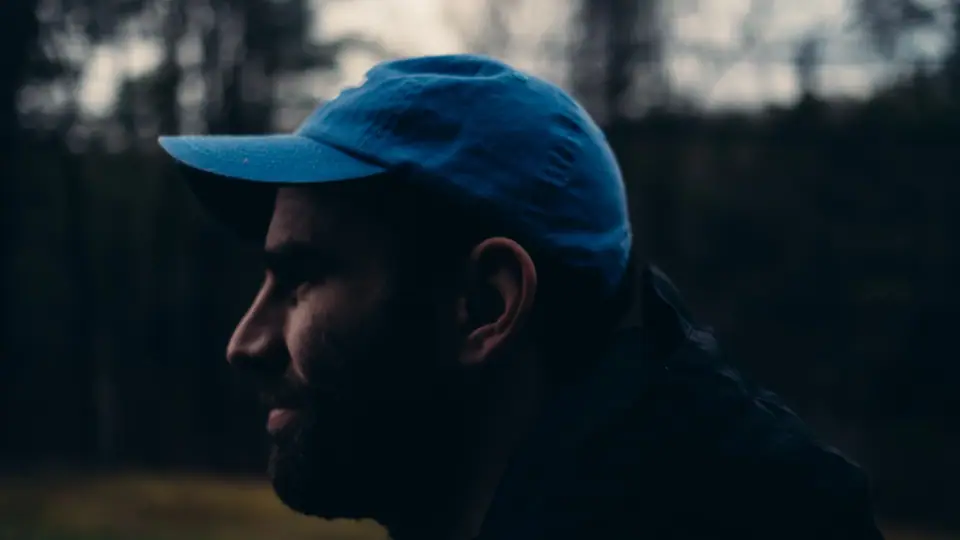A profile wearing a blue cap, illuminated from the side.