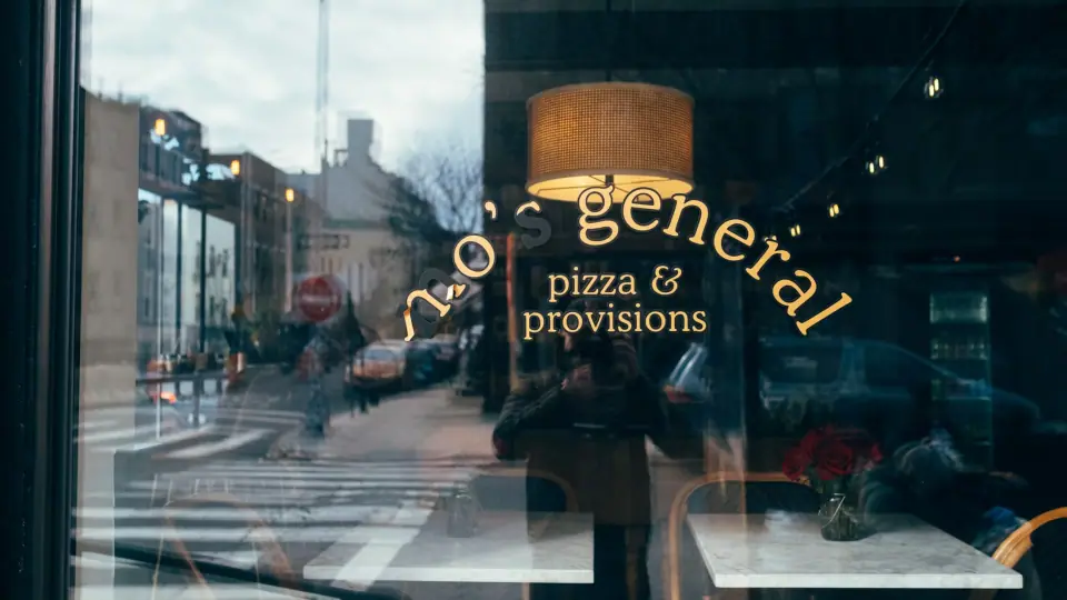Reflected street geometry overlaps gold window lettering in a shop scene.